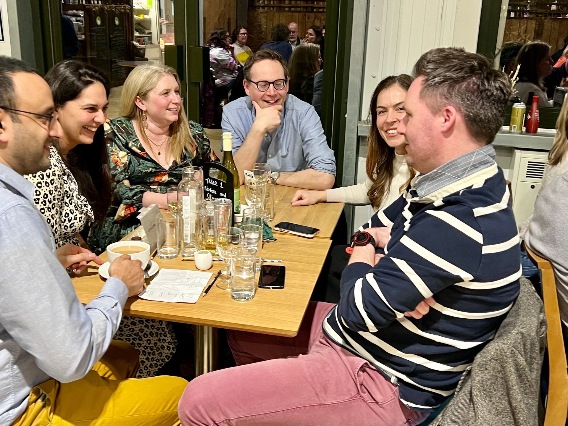 Group of people laughing and talking at a table in a restaurant.