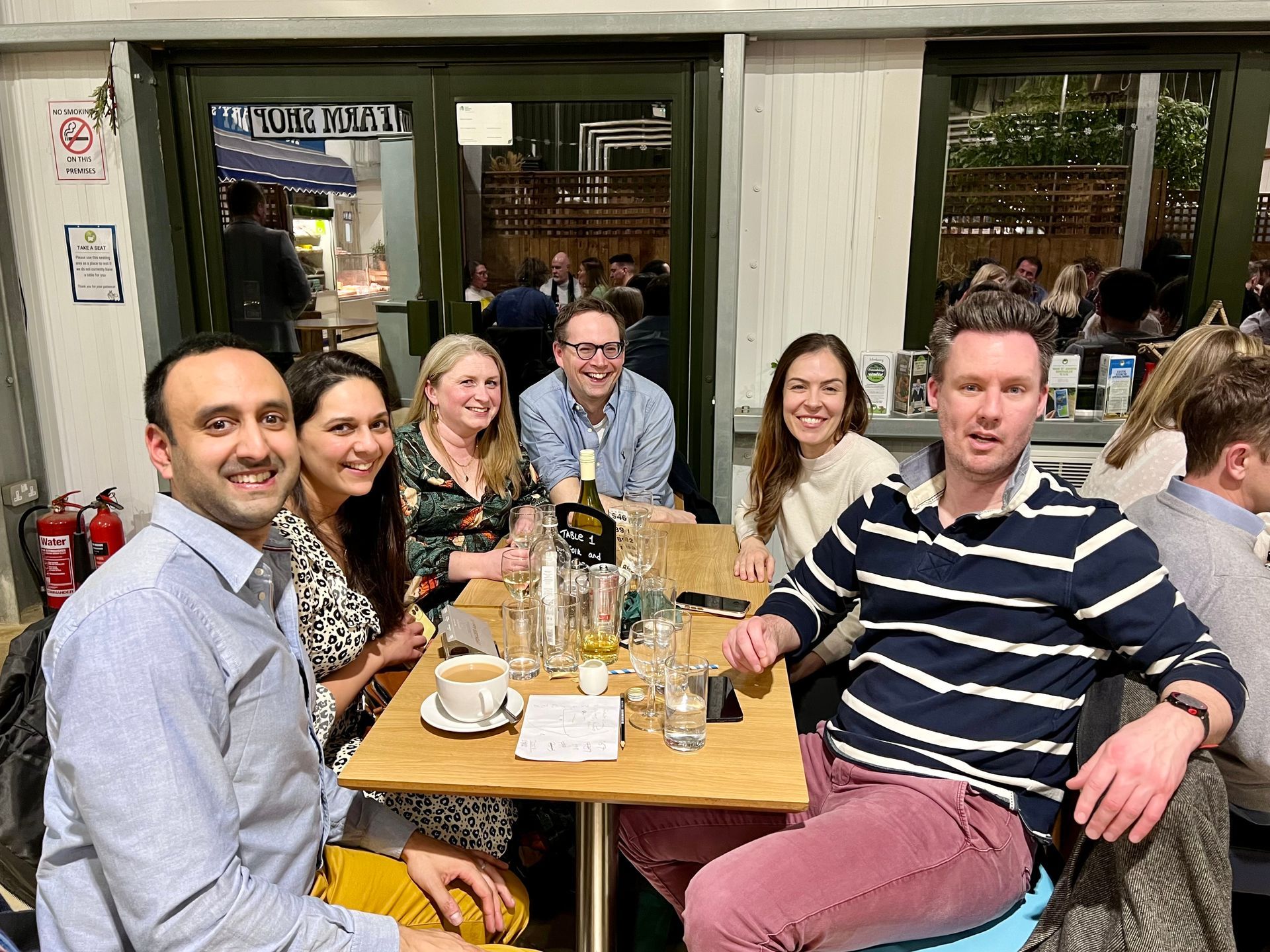 Group of six people smiling around a table in a restaurant.