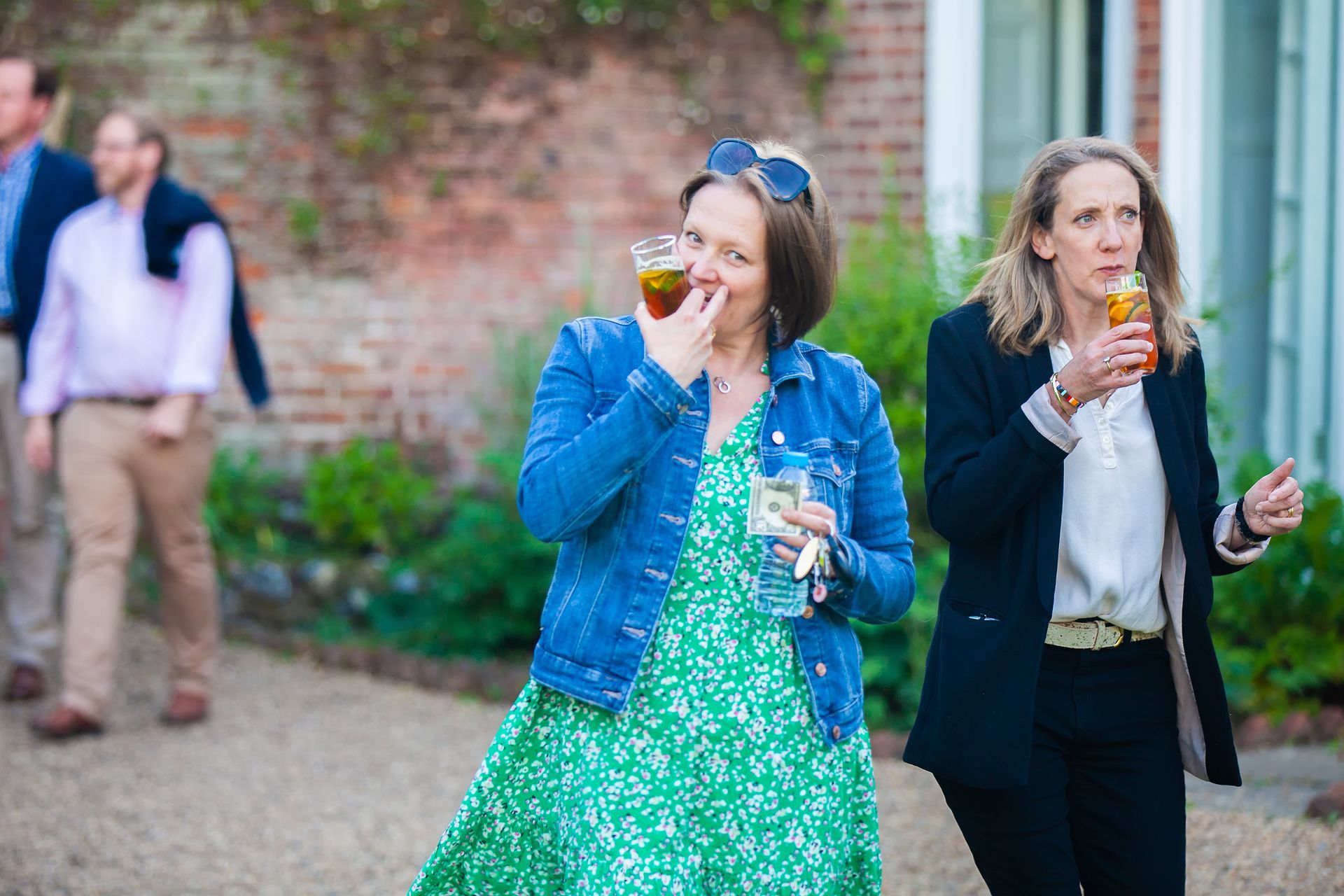 Two women and two men outside; the women sip drinks and the one in green smiles.