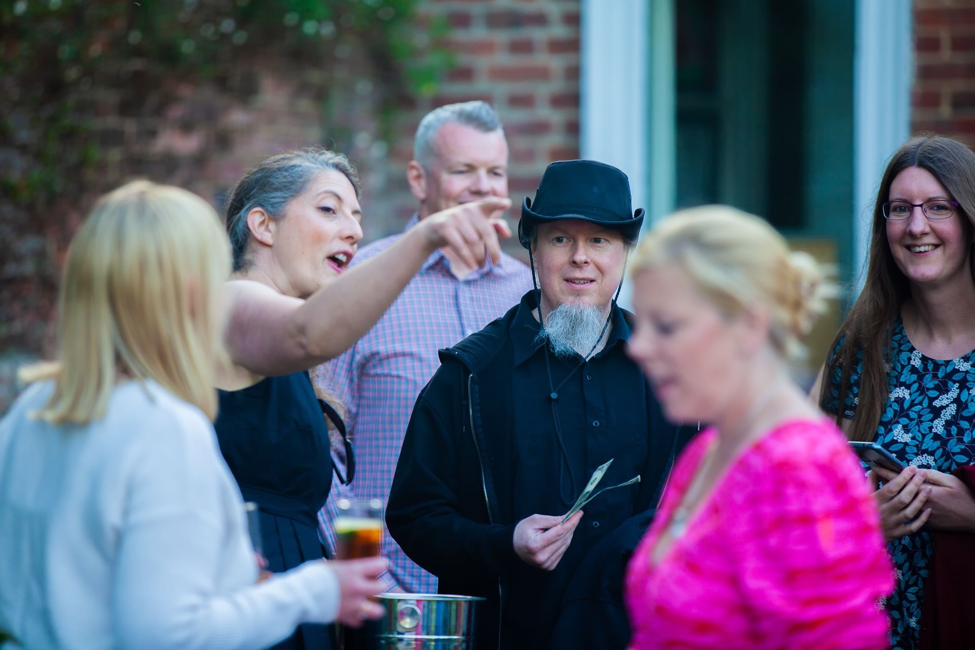Group of people socializing outdoors, with a woman pointing and others smiling.