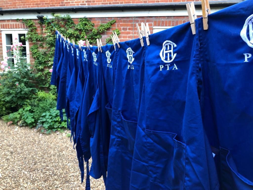 Blue PTA aprons hanging on a clothesline, drying outdoors.