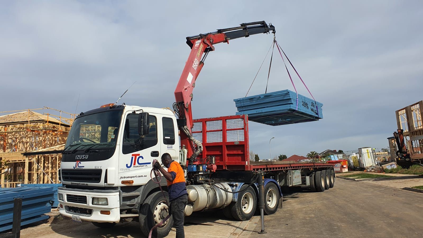 A crane is lifting a blue box from the back of a truck.
