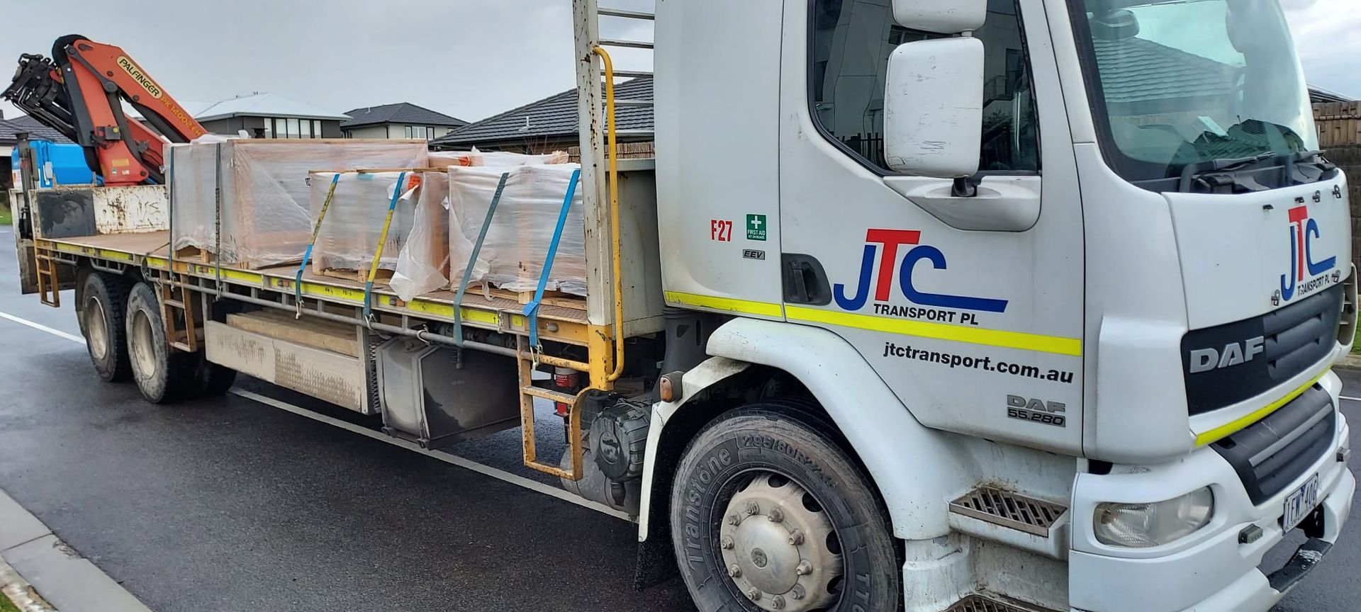 A white truck with a flatbed is parked on the side of the road.
