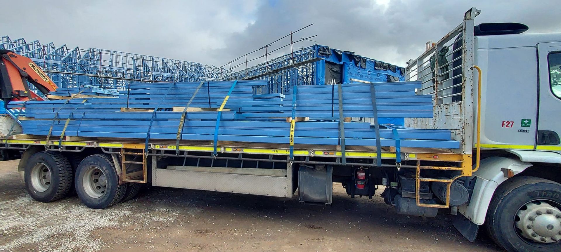 A truck is loaded with blue scaffolding and a crane.
