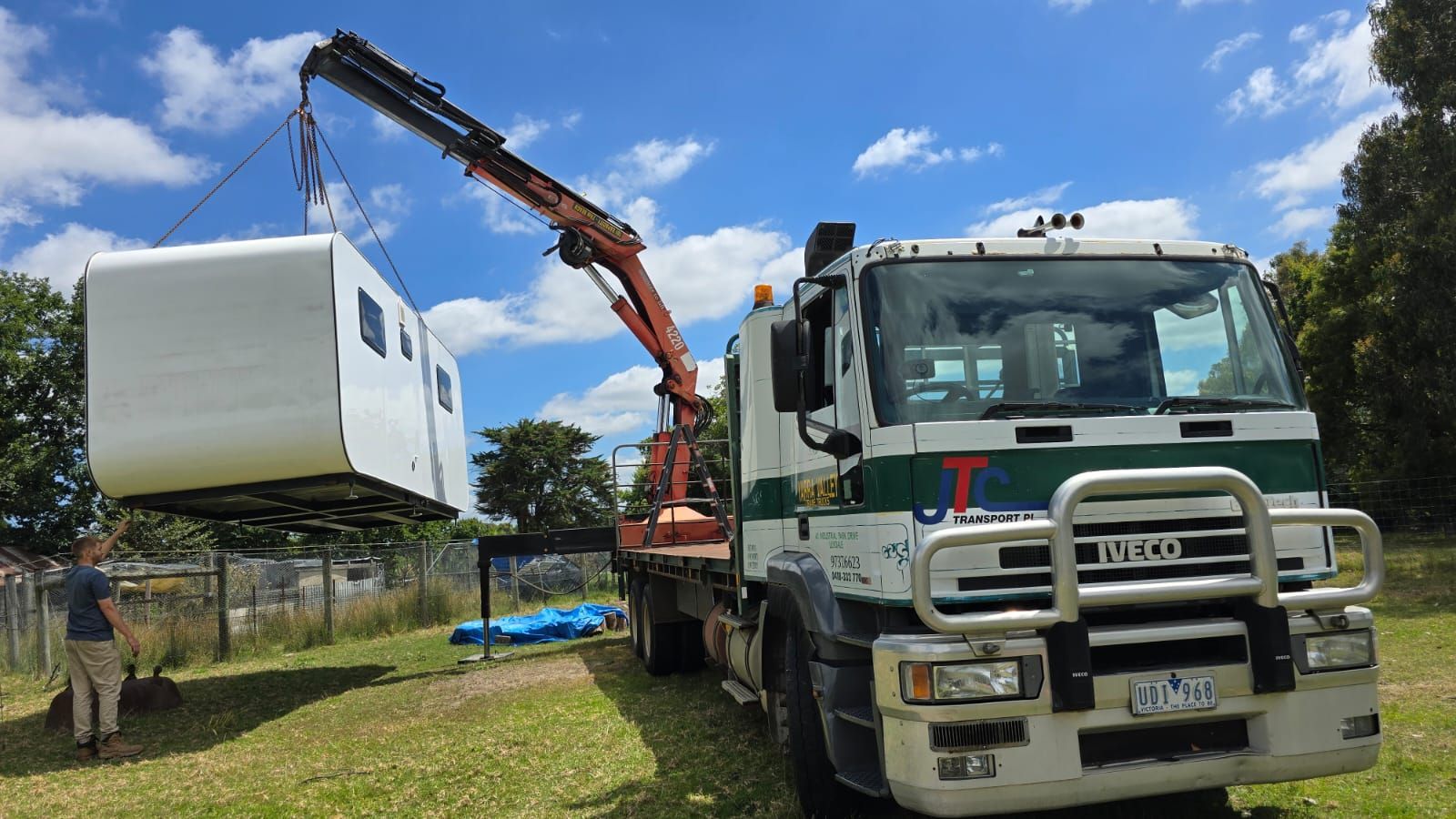 A truck is carrying a container with a crane attached to it.