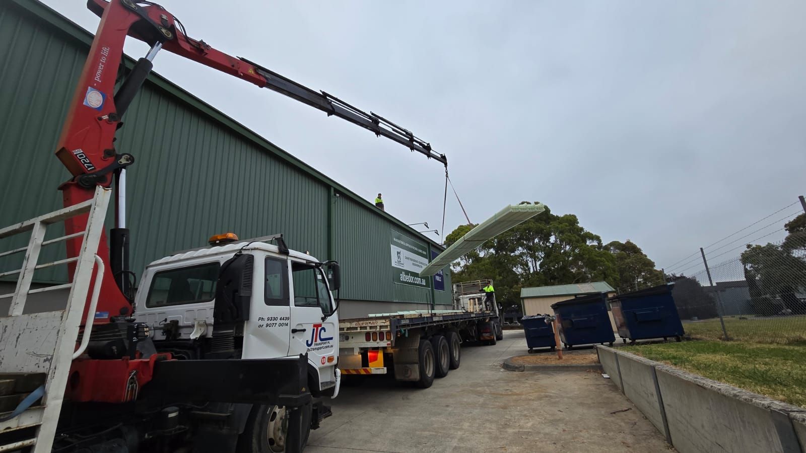 A truck with a crane attached to it is parked in front of a building.