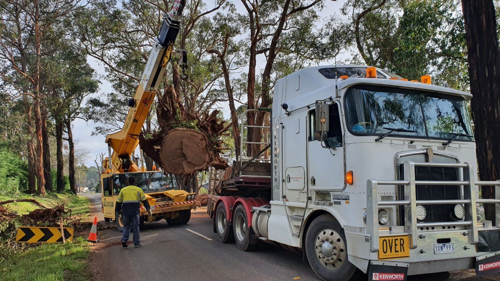 A white semi truck is being towed by a crane.