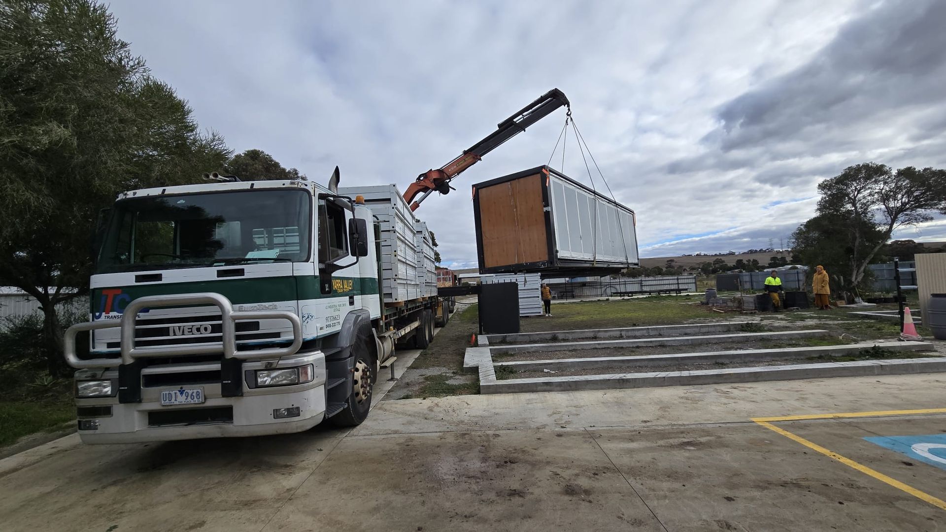 A truck is being lifted by a crane in a field.