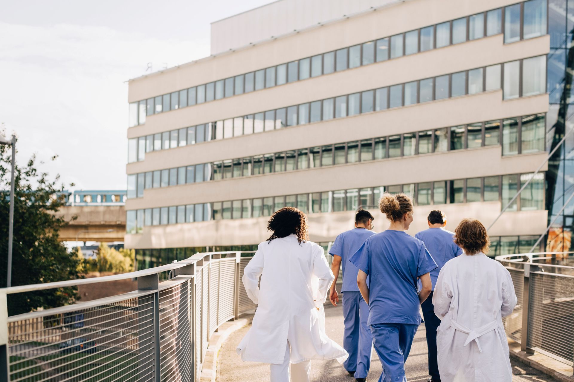 A Group Of Doctors And Nurses Are Walking Towards A Hospital Building — Northcote, AUK — Regency Home & Hospital
