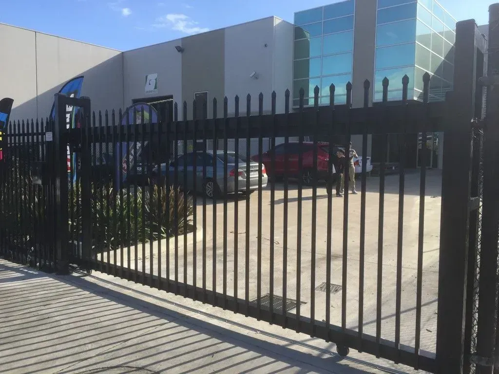 A sliding gate is open in front of a large building.