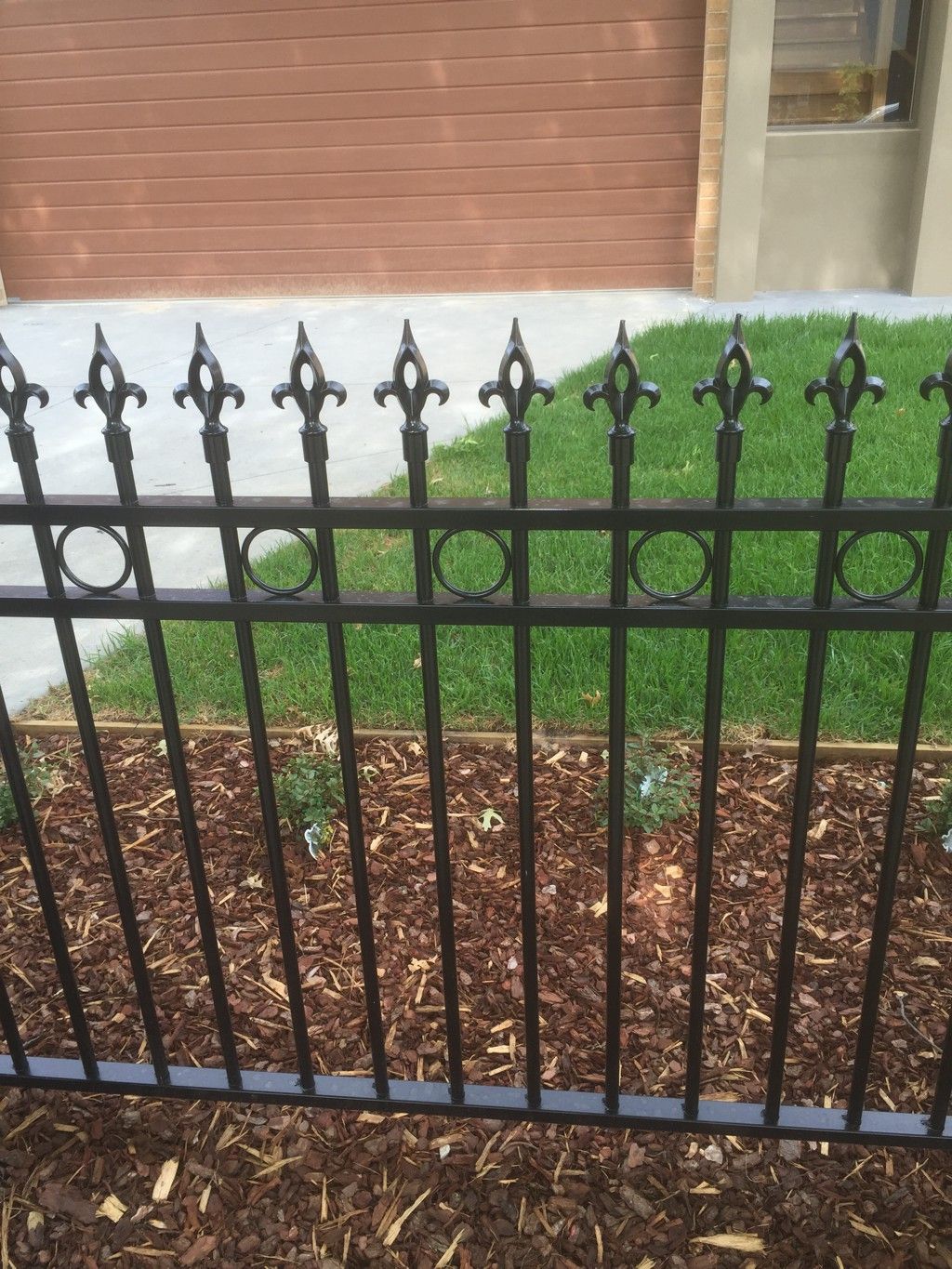 A black wrought iron fence is in front of a brick building.