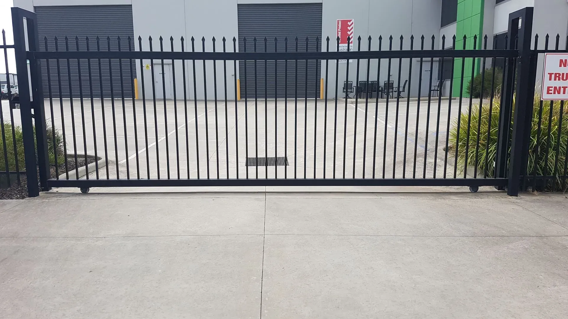 A sliding gate in front of a building with a sign that says no trespassing