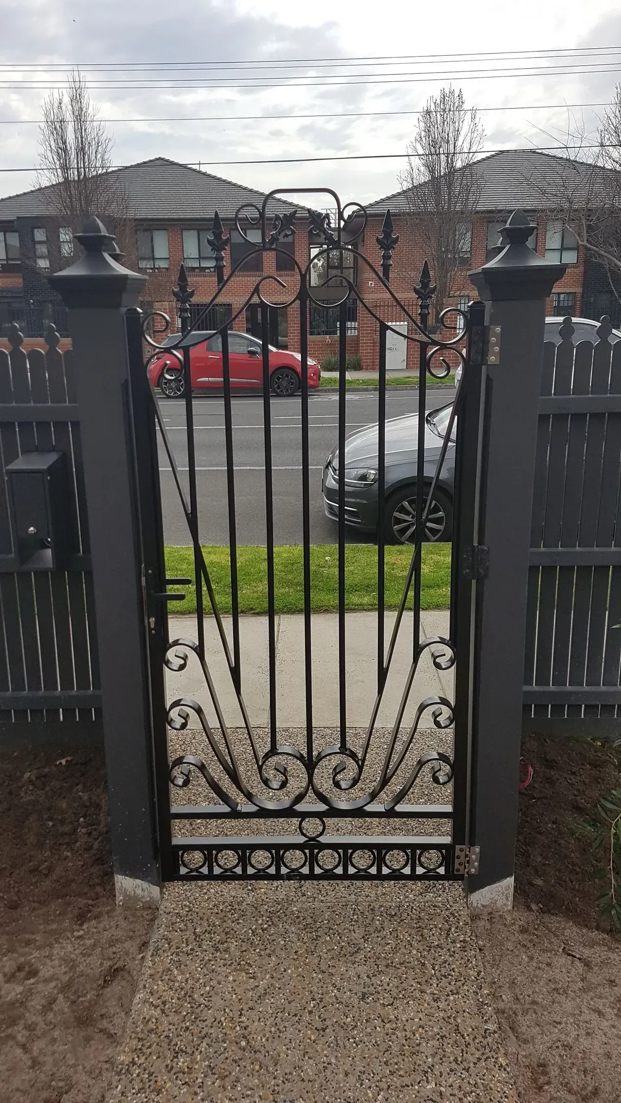 A black gate with a red car driving through it.