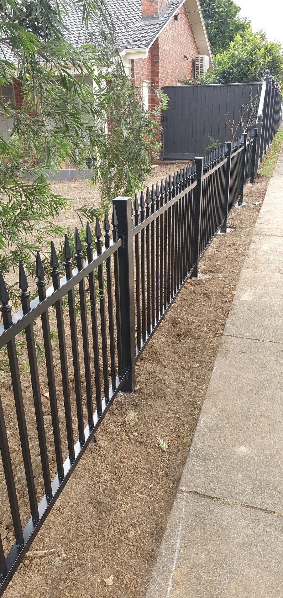 A black metal fence along a sidewalk next to a house.