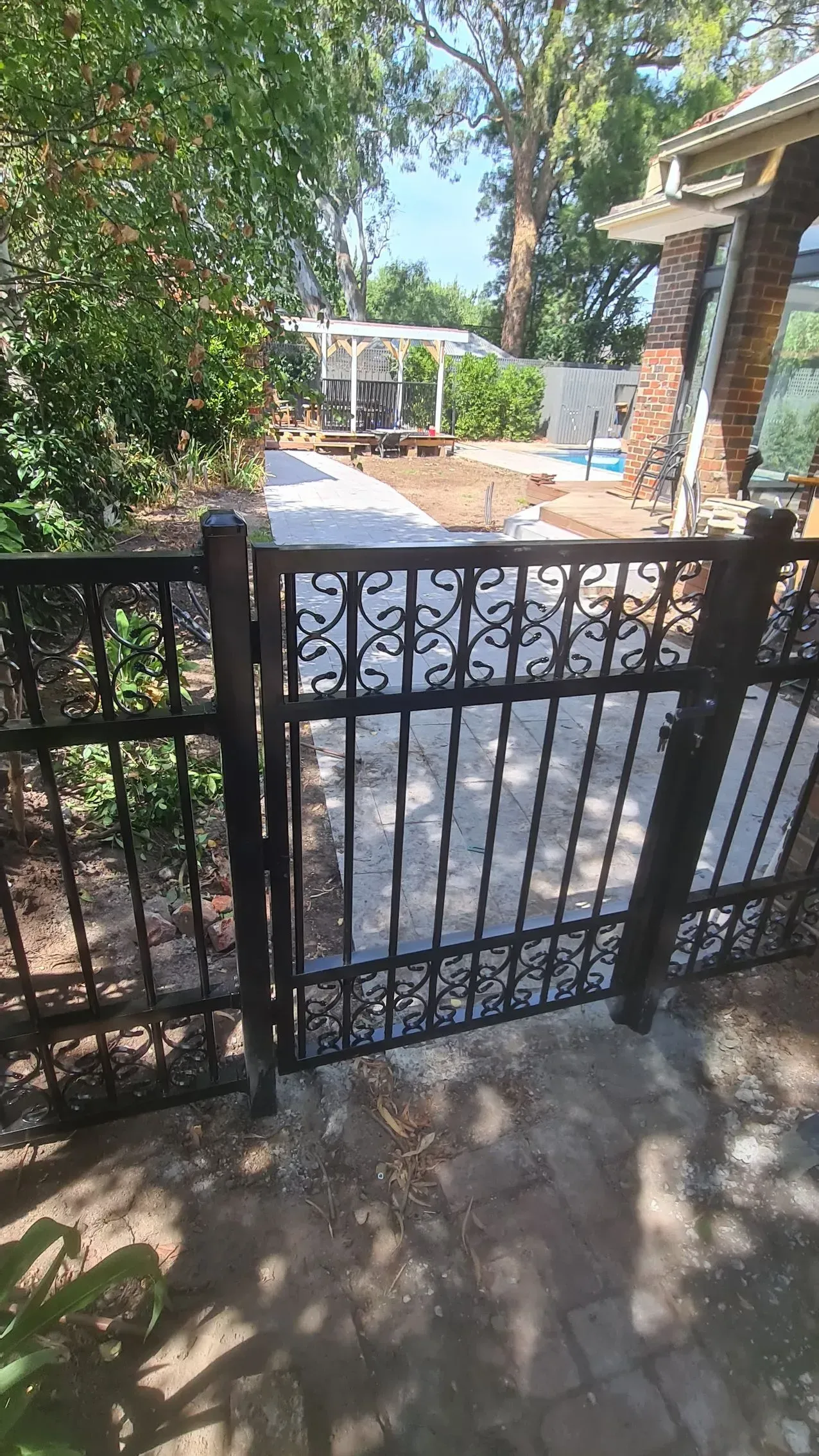 A wrought iron gate leading to a patio in front of a house.