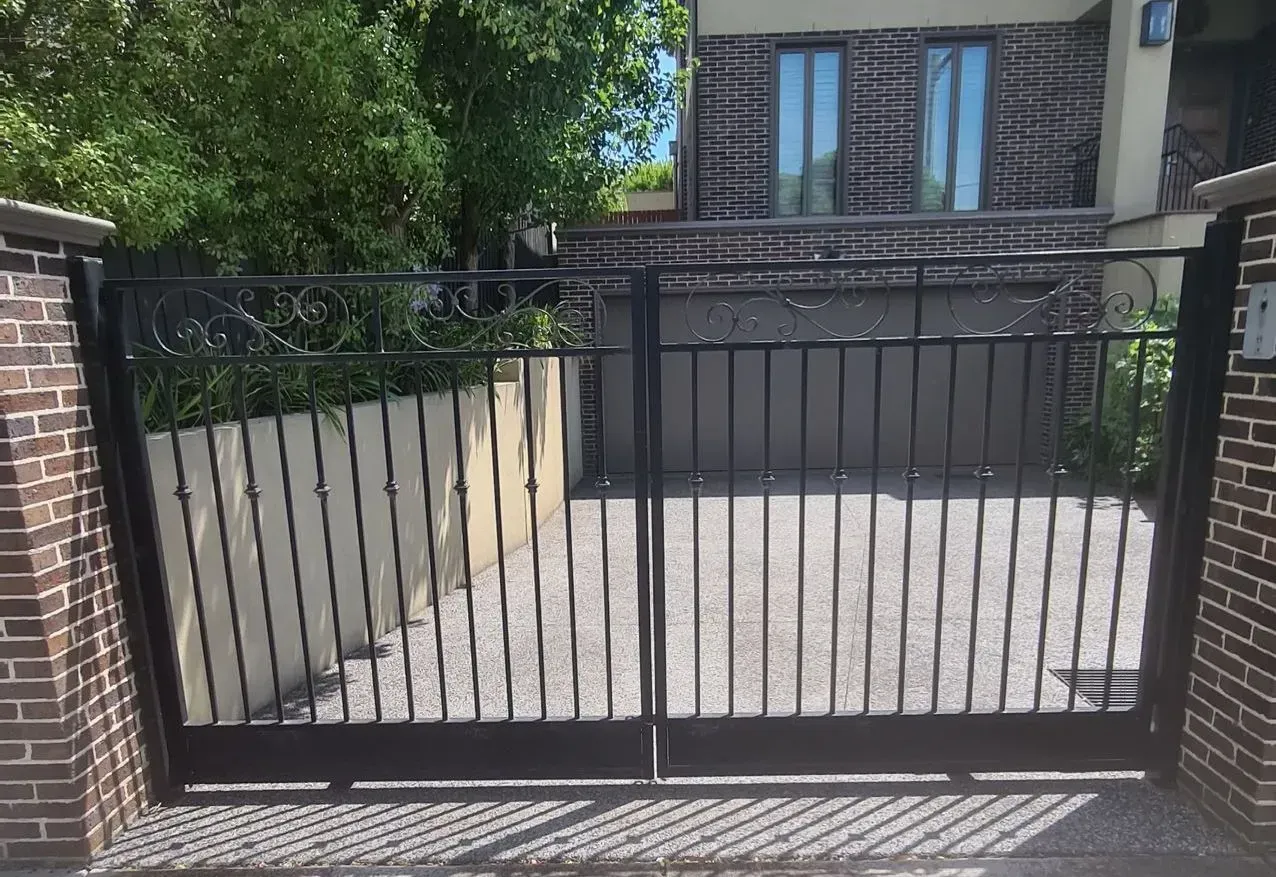 A black gate is open in front of a brick building.