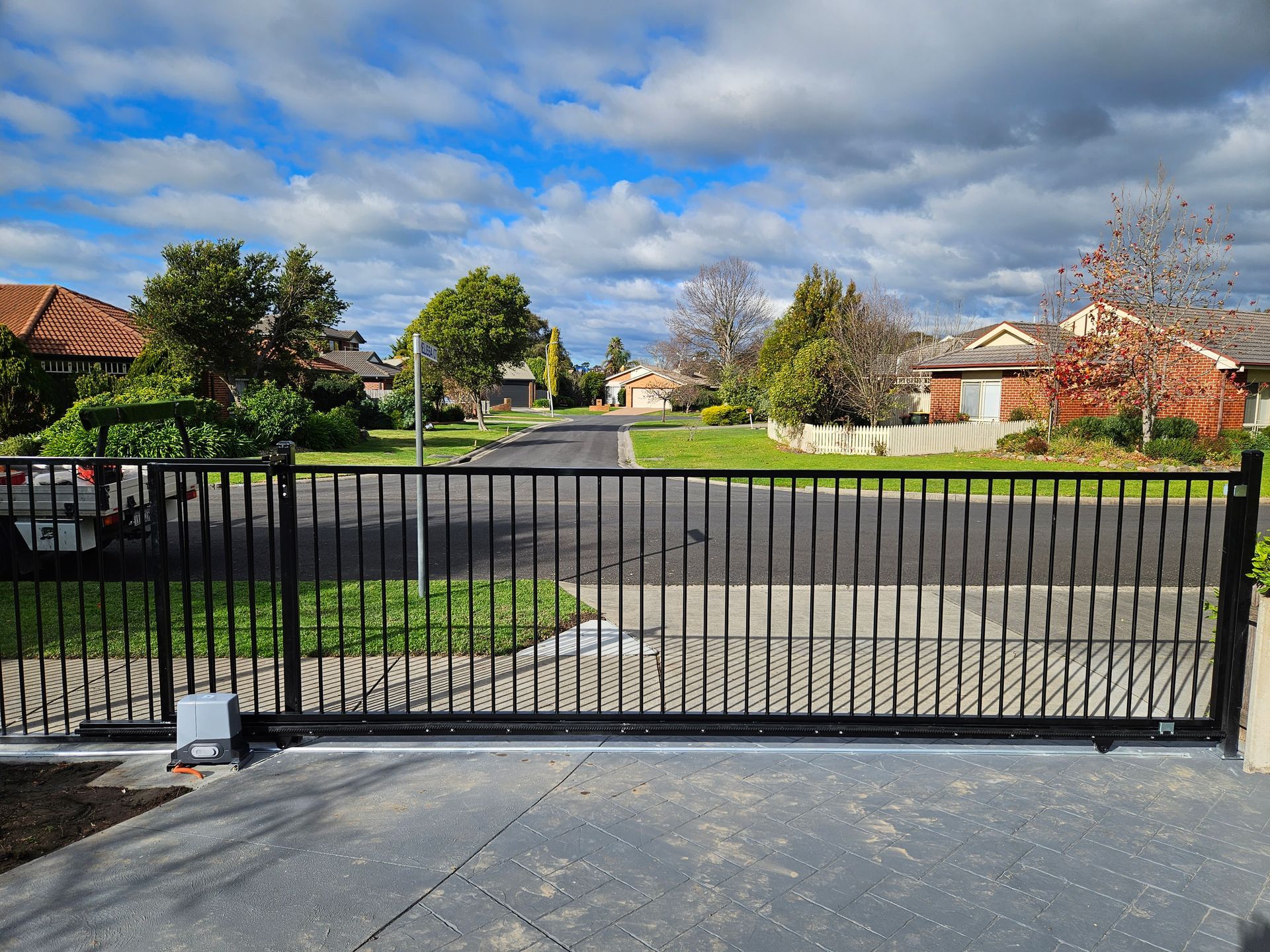 A sliding gate is open to a driveway in a residential area
