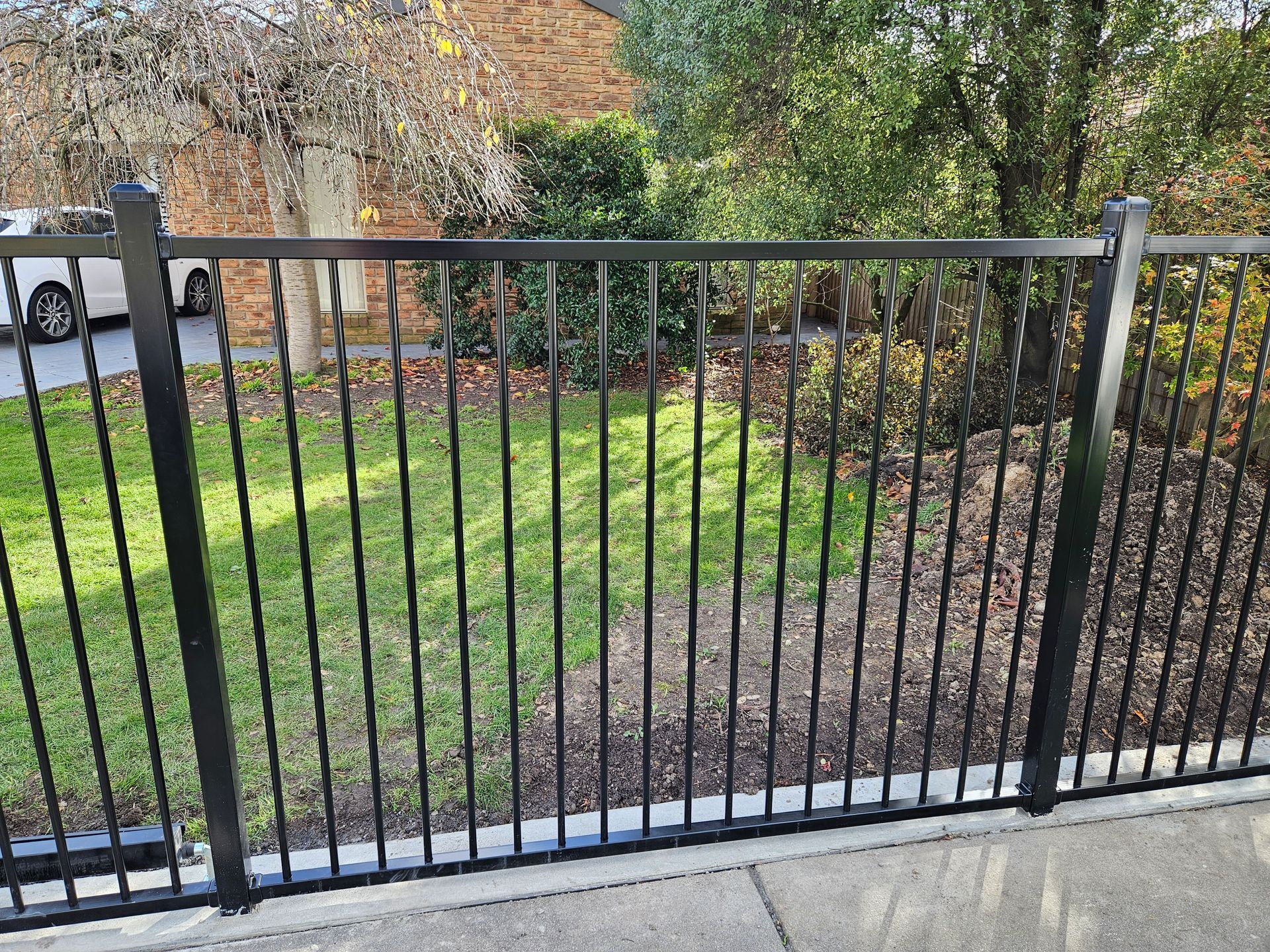 A black metal fence surrounds a lush green field.