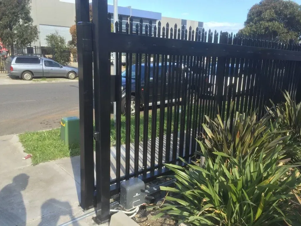 A black fence with a car parked behind it