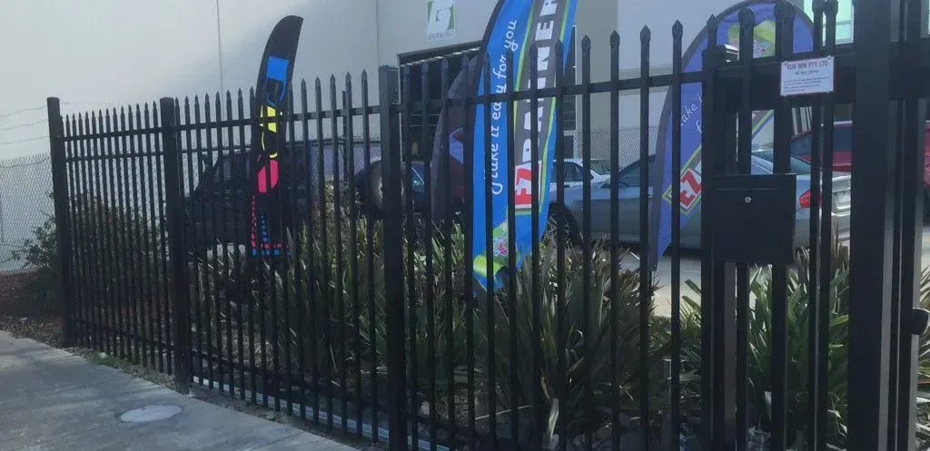 A black metal fence with a mailbox in front of a building.