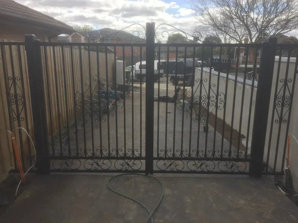 A black wrought iron gate is sitting in front of a house.