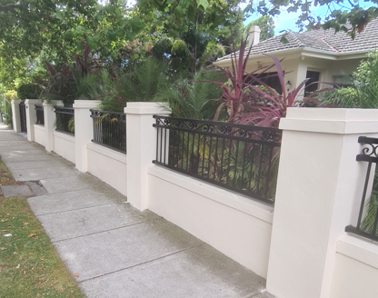 A white fence with a black railing and a house in the background