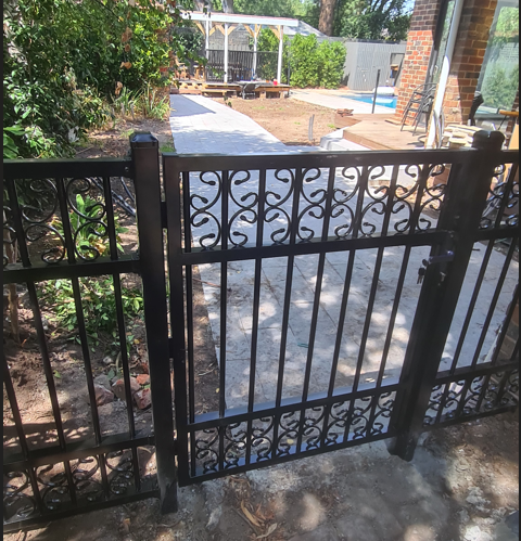 A wrought iron gate leading to a brick walkway