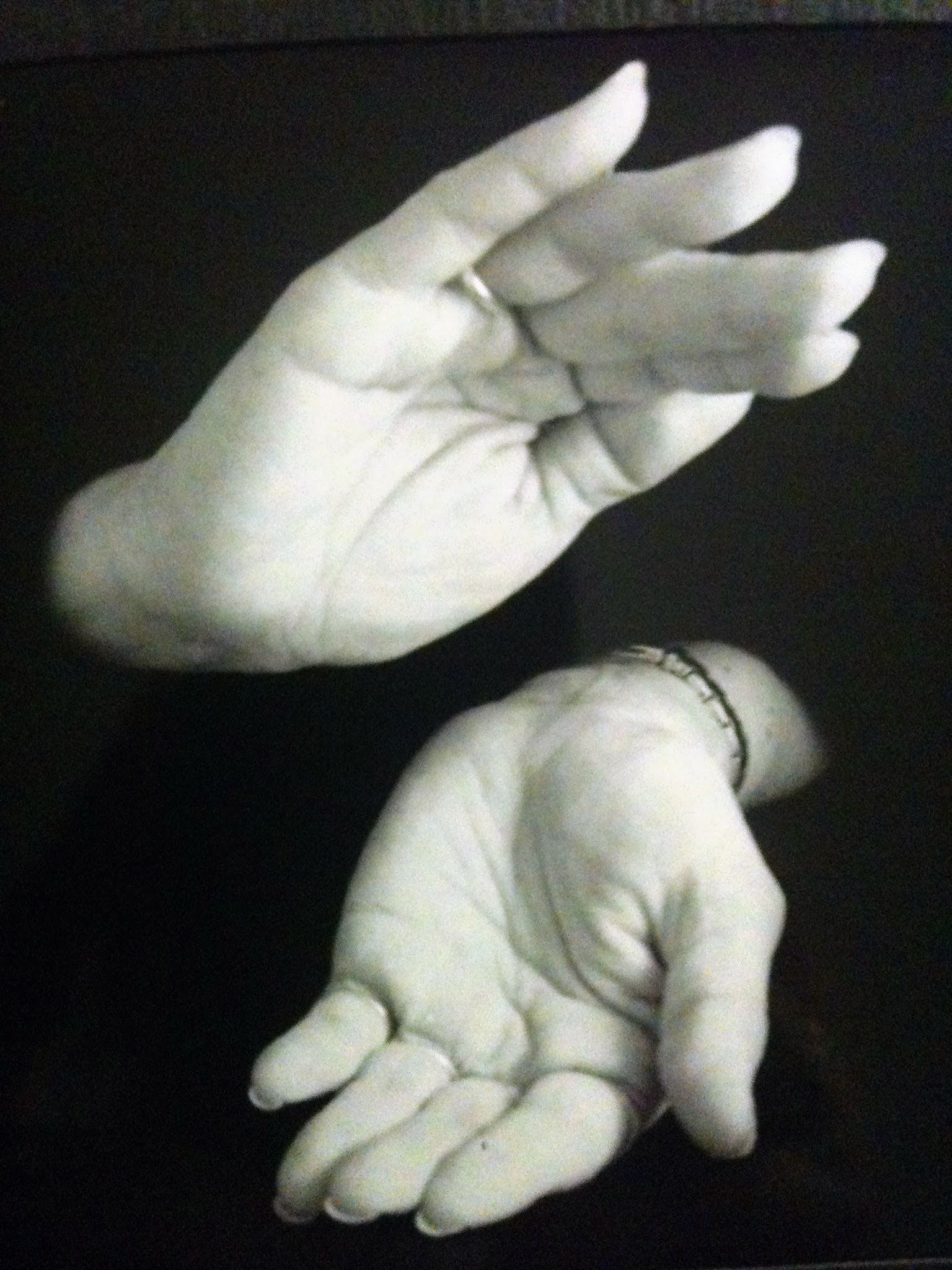 Two cupped hands, one above and one below, in black and white on a dark background