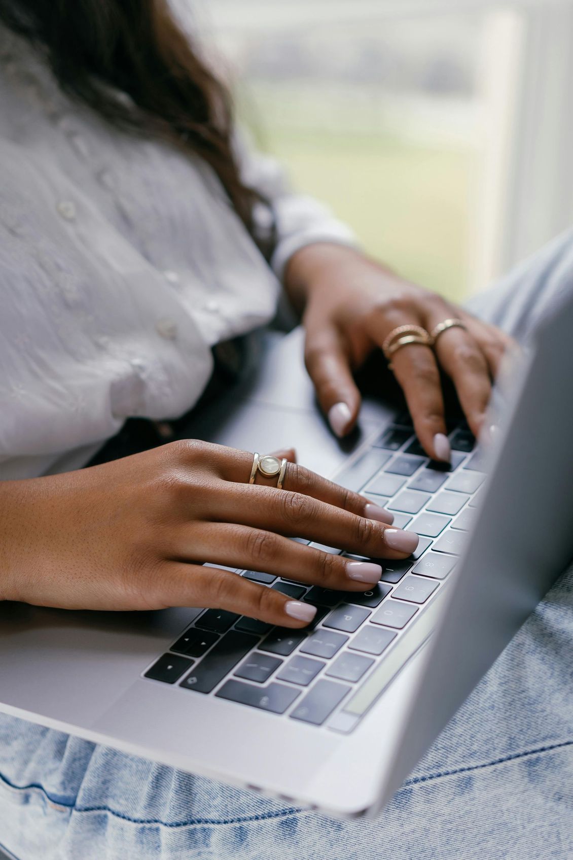 Hands typing on a laptop keyboard for teletherapy in Chesapeake wearing rings and light clothing in a casual setting