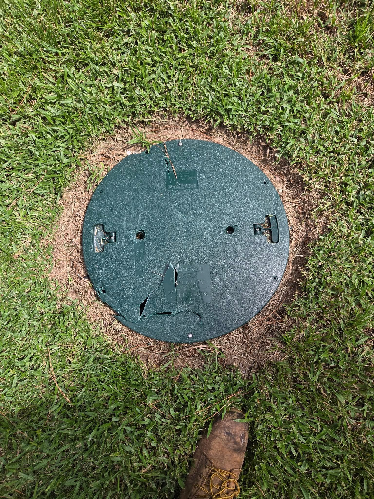Green circular utility cover in grass.