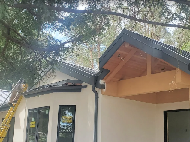 Construction site with cream-colored stucco, dark trim, and a wooden roof overhang — Modern House Construction with Metal Roof in Napa, CA Construction site with cream-colored stucco, dark trim, and a wooden roof overhang — Modern House Construction with Metal Roof in Napa, CA
