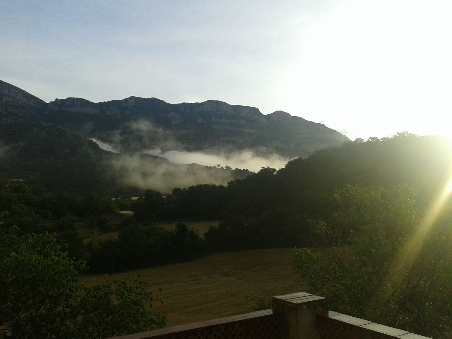 El sol brilla a través dels núvols sobre les muntanyes
