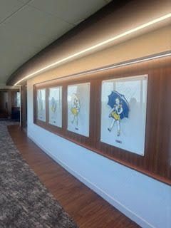 A hallway with four framed illustrations of a figure holding an umbrella.