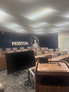 Empty Morton auditorium with rows of seats facing a stage with a large screen.