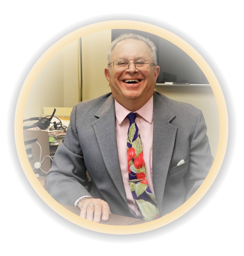 A man wearing glasses and a tie smiles for the camera