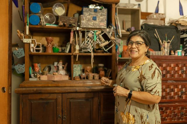 A woman is standing in front of a wooden cabinet in a room.