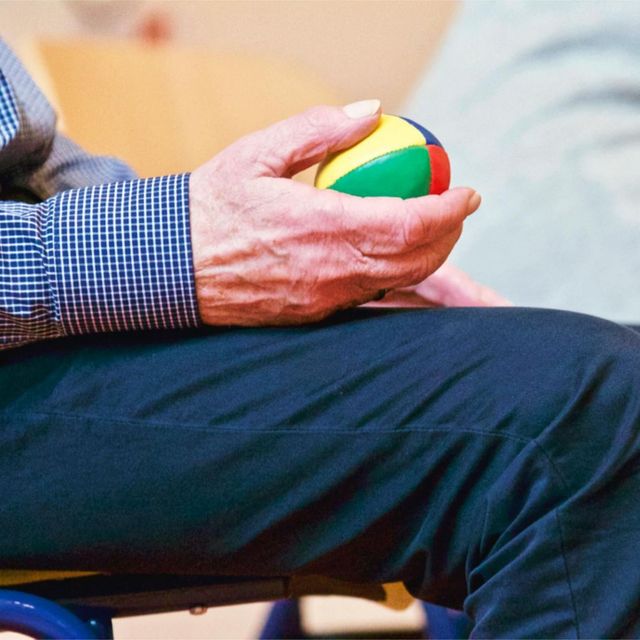 A man in a plaid shirt is holding a colorful ball