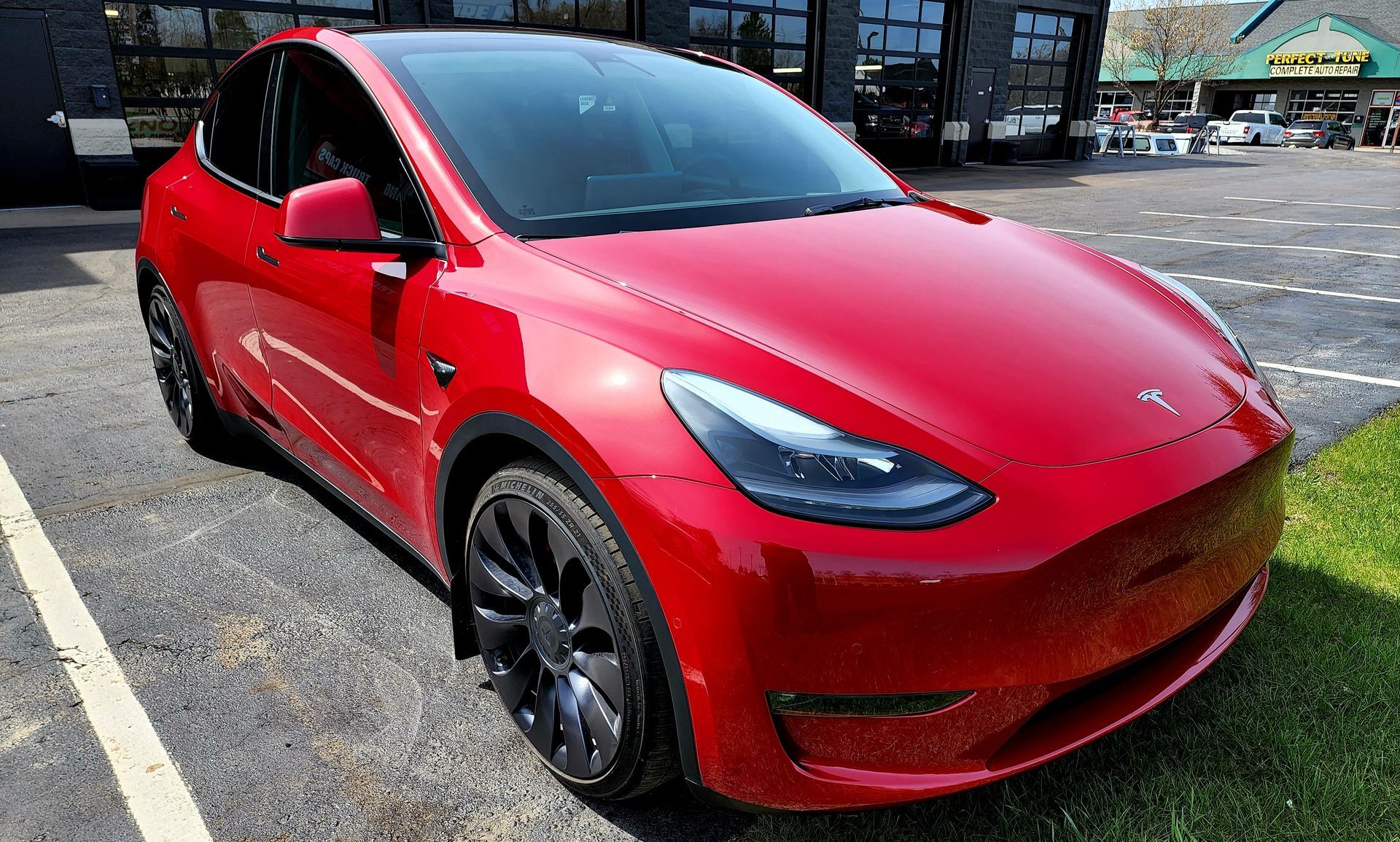 A red tesla model y is parked in a parking lot.
