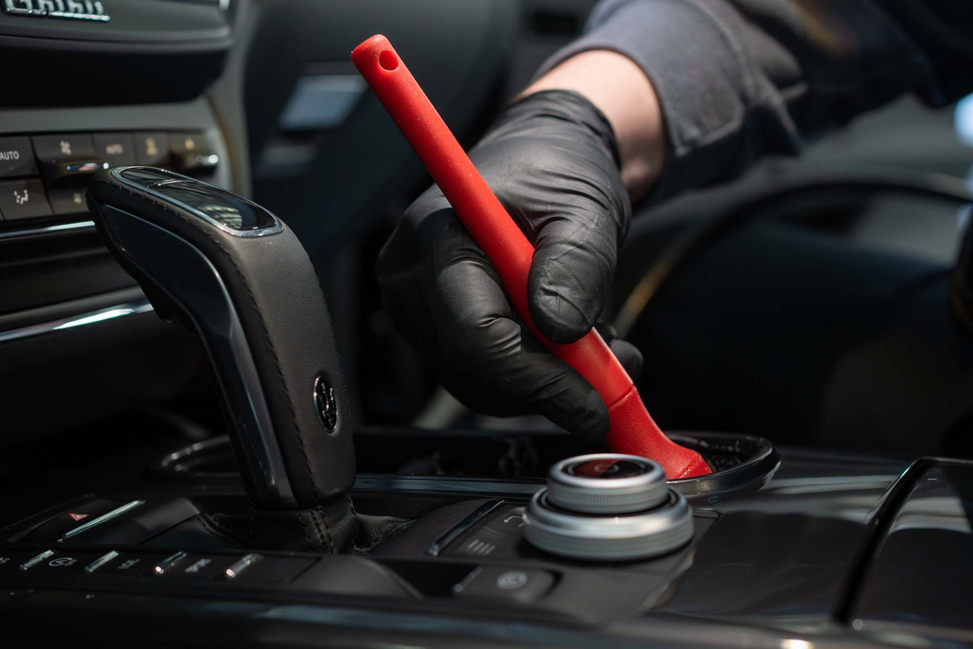 A person wearing black gloves is cleaning the dashboard of a car.