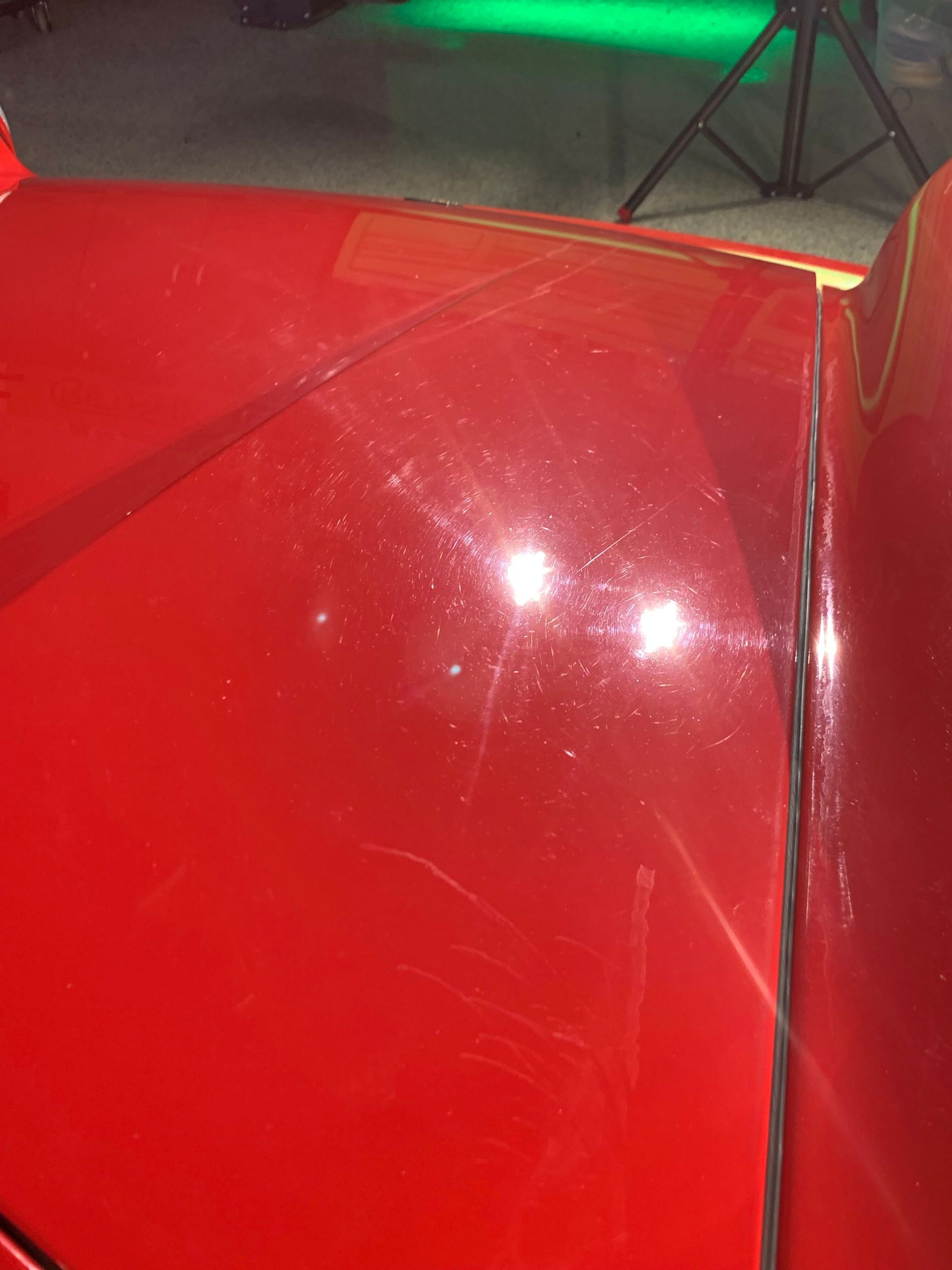 A close up of the hood of a red car in a garage.