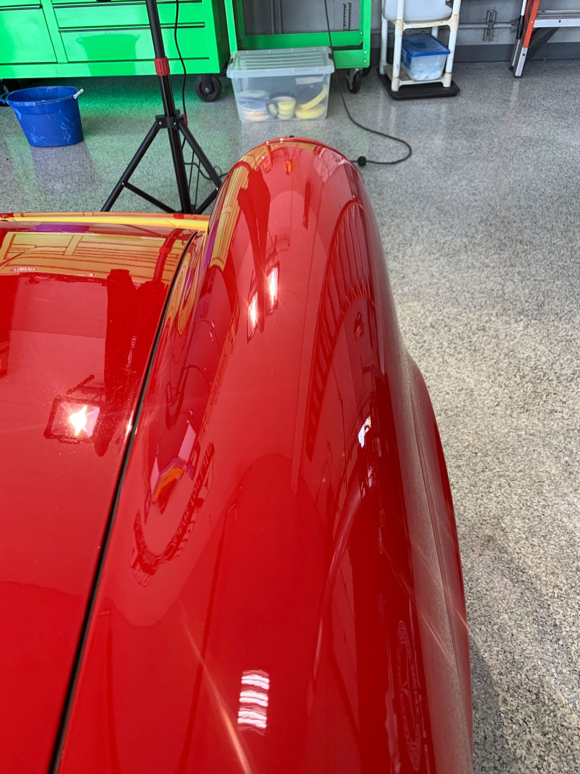 A close up of a red car 's fender in a garage.