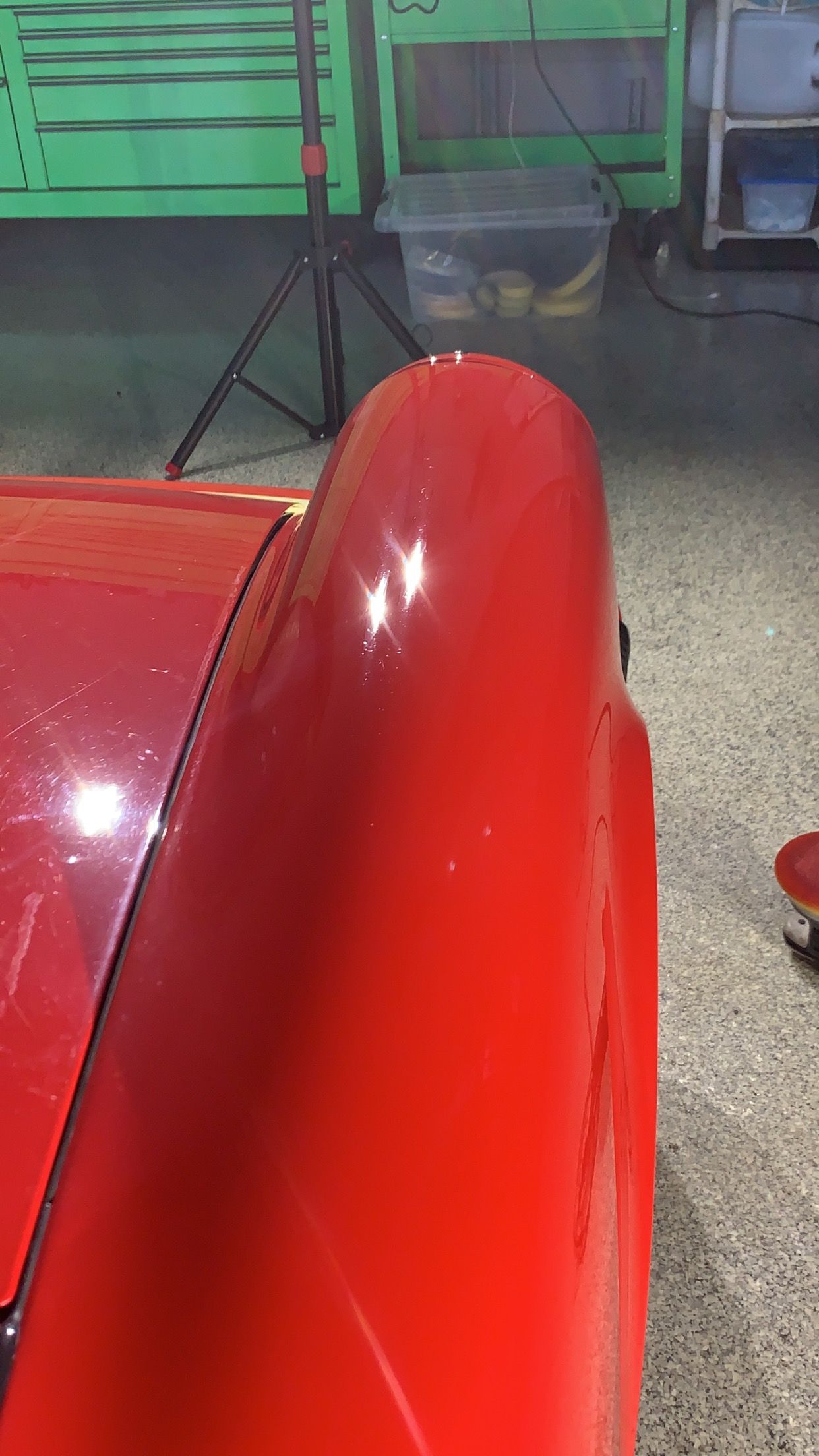 A close up of a red car 's fender in a garage.