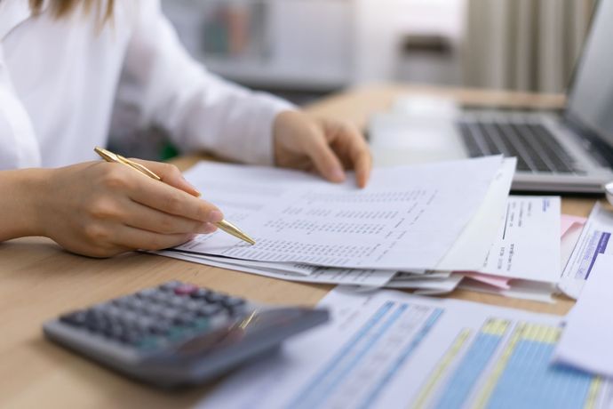 A woman is sitting at a desk with a laptop and a calculator.