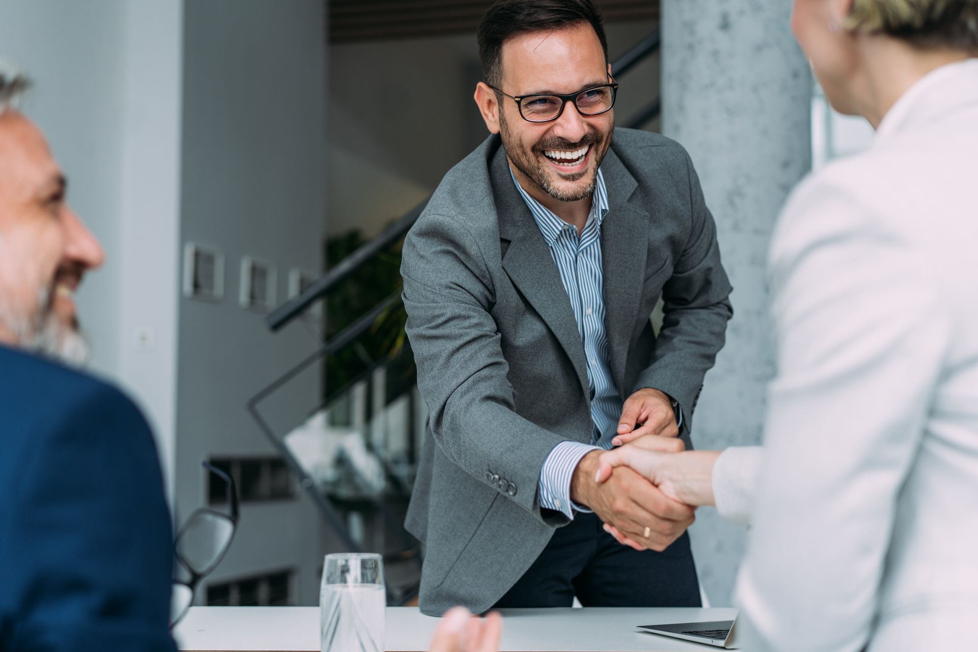 A man in a suit is shaking hands with a woman in an office.