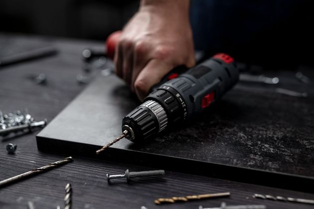 A person is using a drill to drill a hole in a piece of wood.
