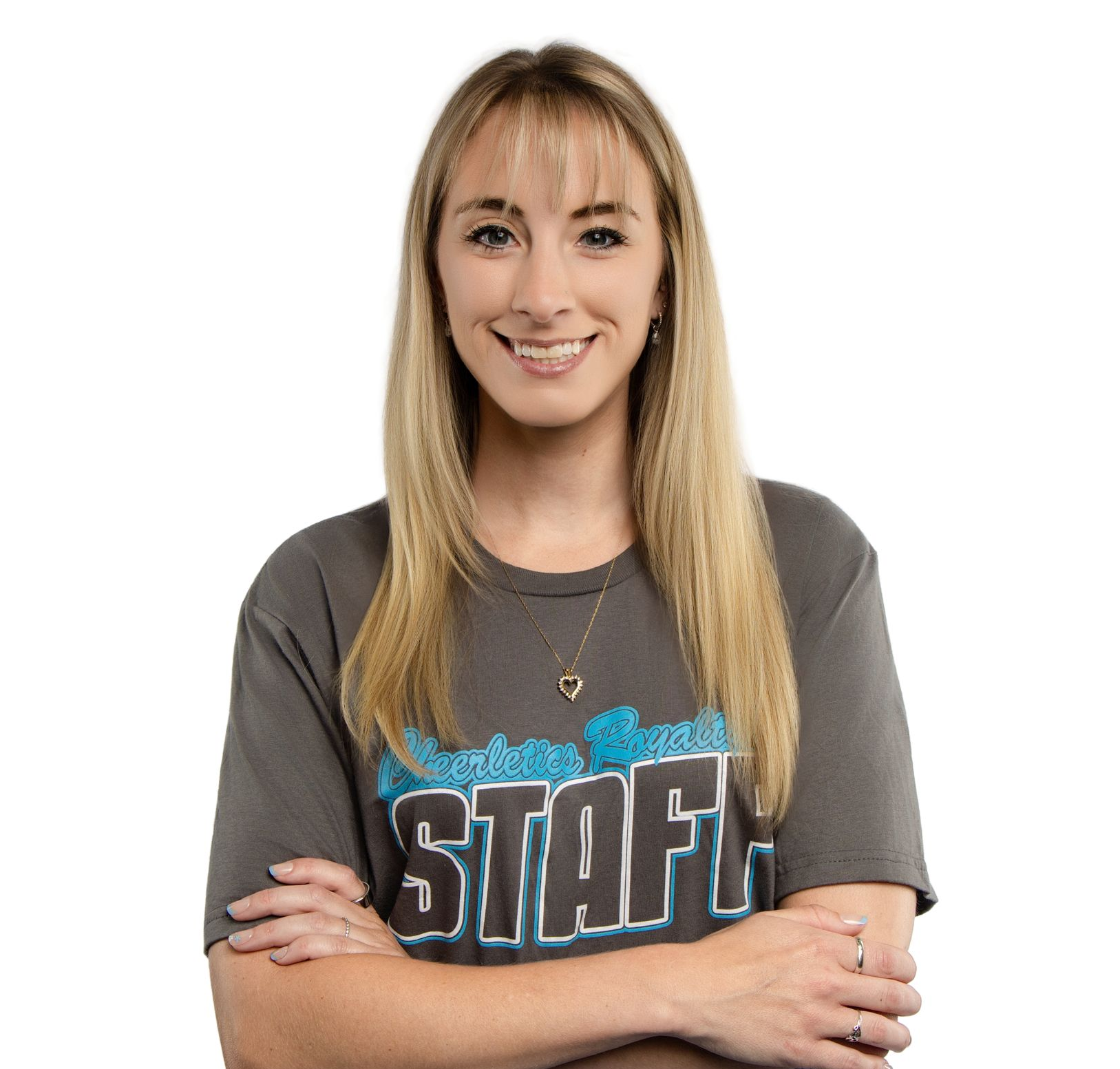 A man in a blue shirt is smiling with his arms crossed.