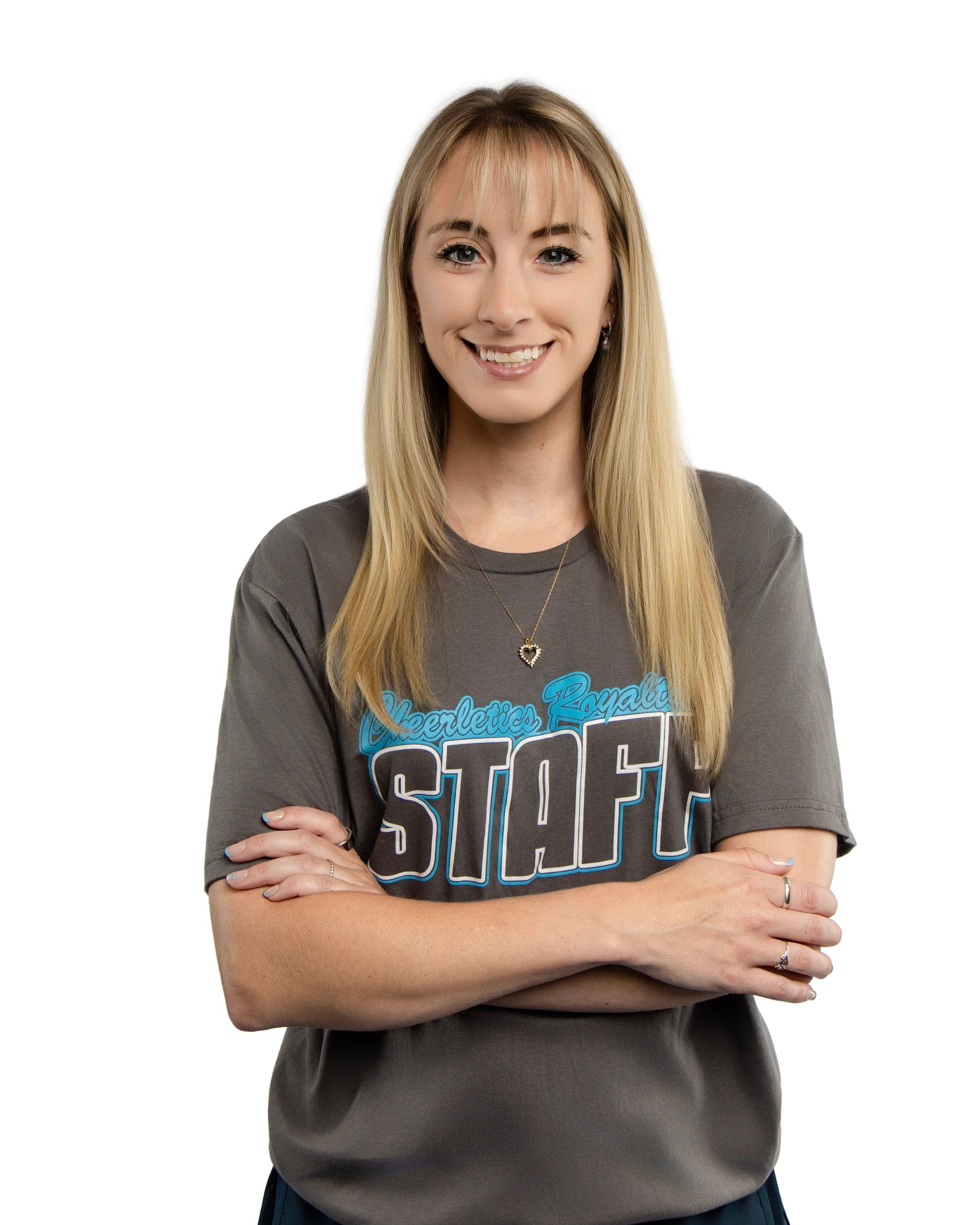 A woman with curly hair is smiling with her arms crossed.