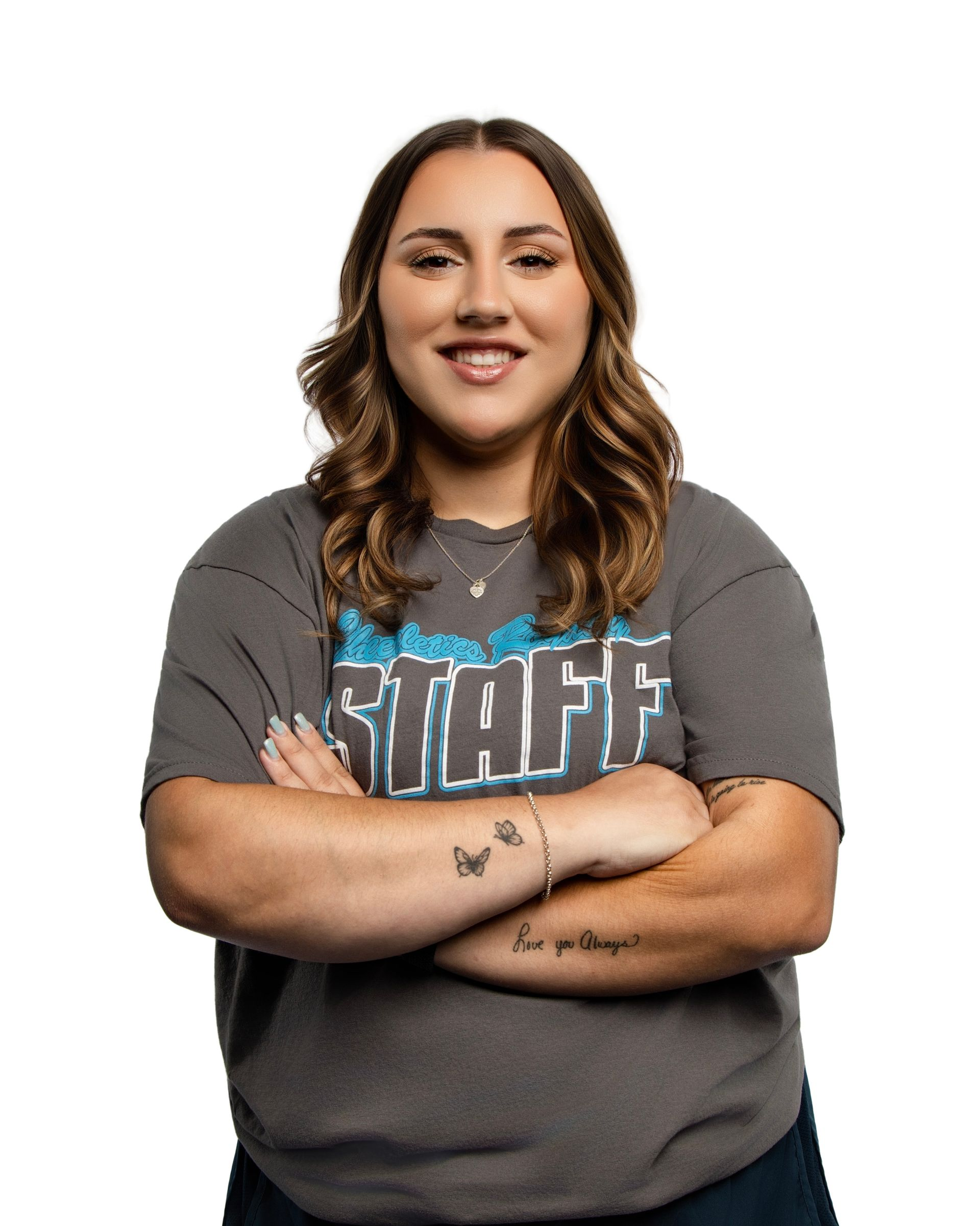 A woman with curly hair is smiling with her arms crossed.