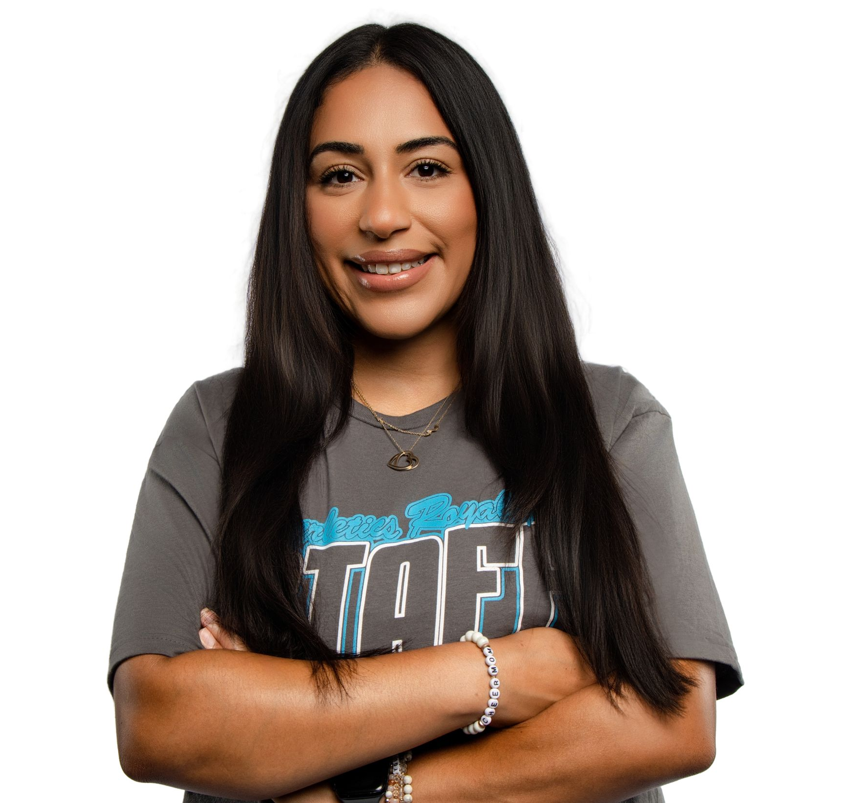 A man in a blue shirt is smiling with his arms crossed.