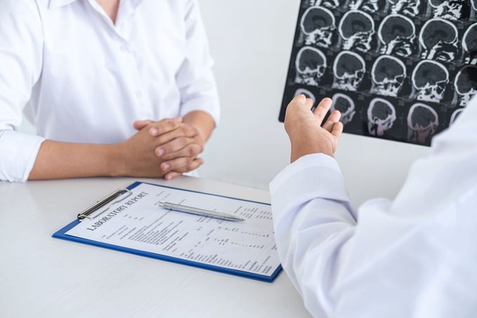 Il medico esamina la scansione cerebrale con il paziente, seduto alla scrivania.